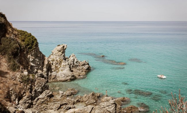 Scogliera rocciosa si affaccia su un mare limpido e azzurro.