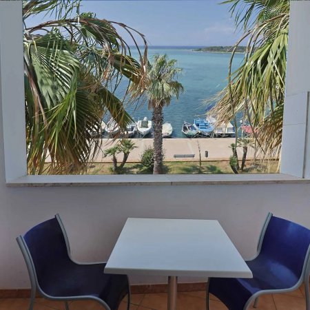Tavolino e sedie sul balcone con vista mare.