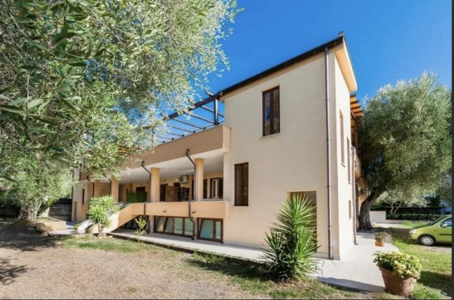 Edificio beige con piante e alberi.