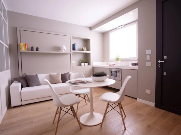 Soggiorno minimalista con tavolo bianco e divano.