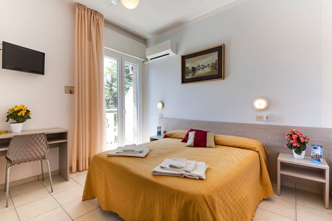 Camera con letto matrimoniale, TV e balcone.