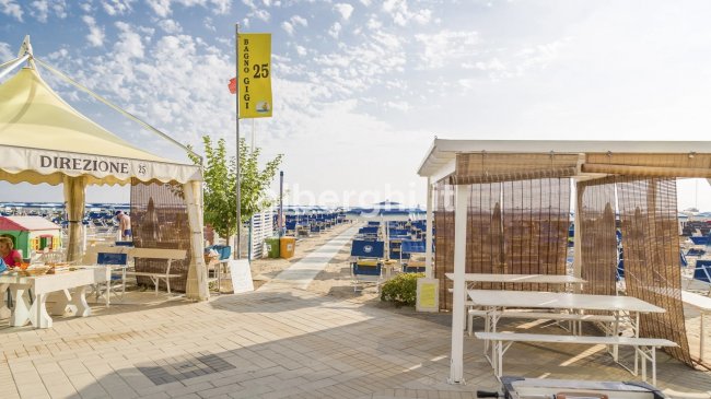 Spiaggia attrezzata con ombrelloni e sedie blu.