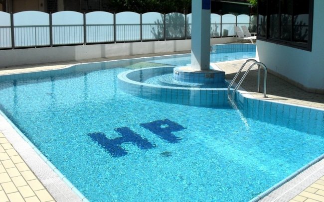 Piscina azzurra con scala e colonna. Lettere HP sul fondo.