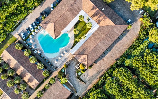 Veduta aerea di un complesso con piscina circondato da alberi.