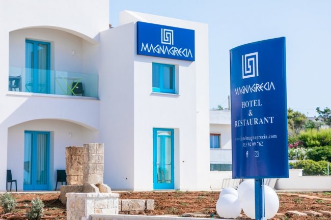 Facciata di un hotel bianco con insegne blu.