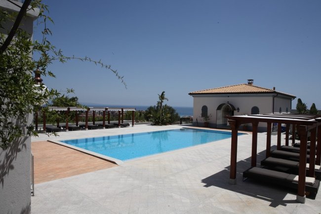 Piscina all'aperto con vista mare e sdraio.