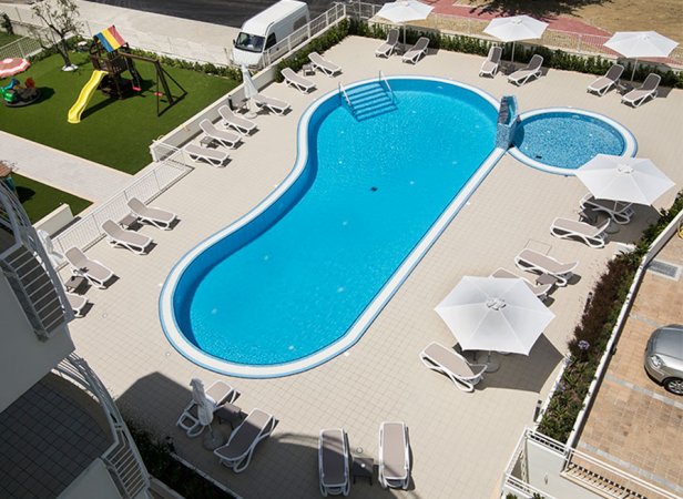 Piscina a forma di fagiolo con lettini e ombrelloni.
