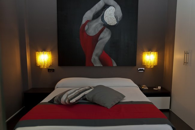 Camera da letto con quadro di ballerina e luci soffuse ai lati del letto.