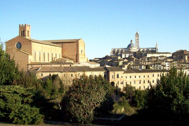 Vista sulla città con edifici storici e vegetazione.