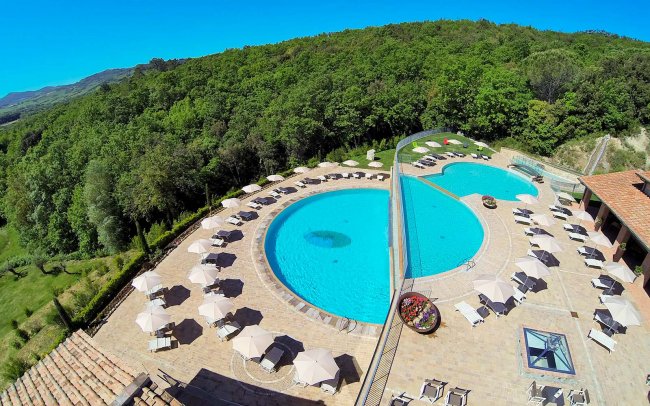Due piscine all'aperto circondate da ombrelloni.