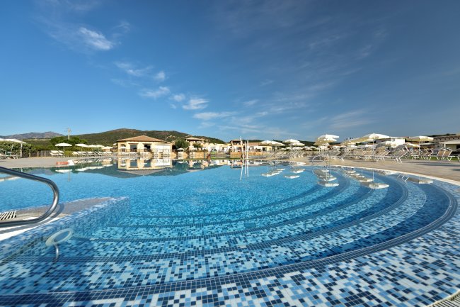 Piscina azzurra con ombrelloni e sdraio.