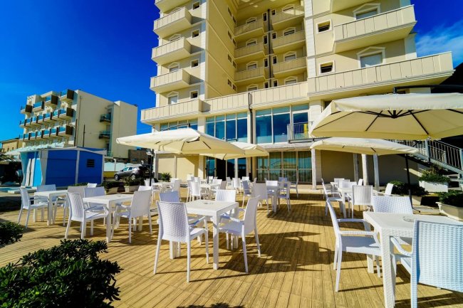 Terrazza con tavoli bianchi e ombrelloni.