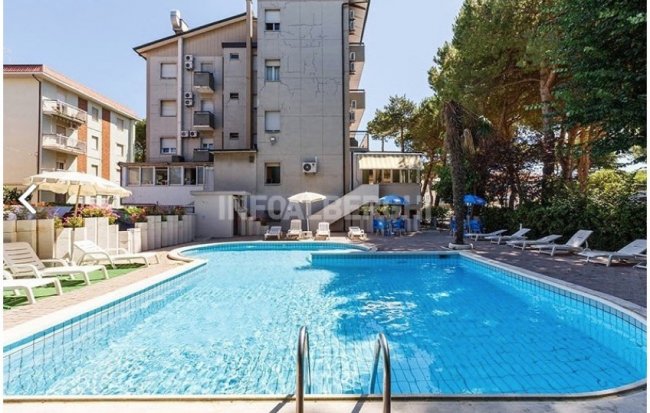 Piscina all'aperto circondata da sedie a sdraio e ombrelloni.