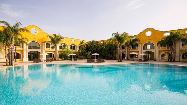 Ampia piscina con edificio giallo sullo sfondo.
