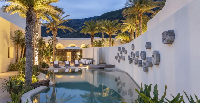 Piscina all'aperto con palme e decorazioni murali.