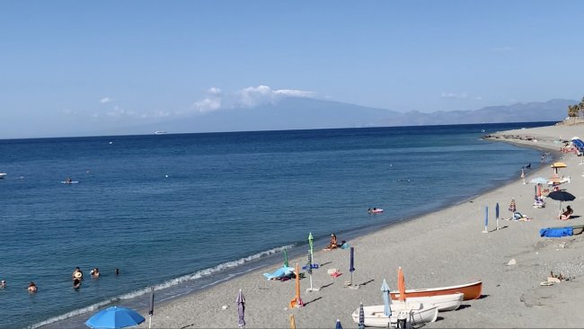 Spiaggia con mare blu e bagnanti.