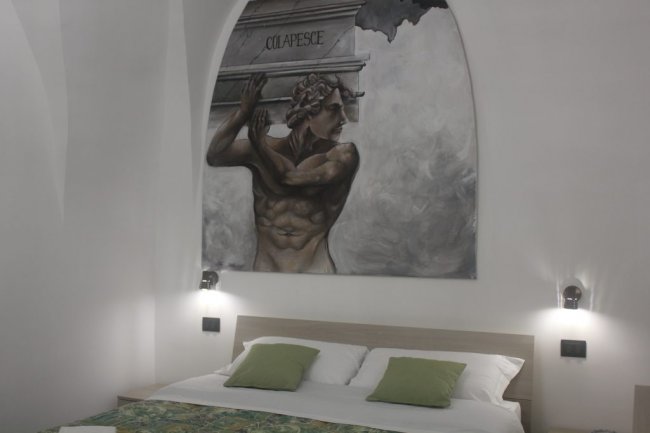 Camera con murale e letto matrimoniale.