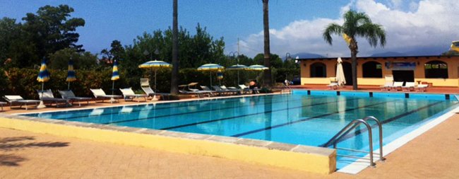 Piscina all'aperto con lettini e ombrelloni.