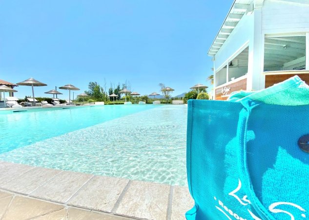 Piscina all'aperto con ombrelloni e lettini.