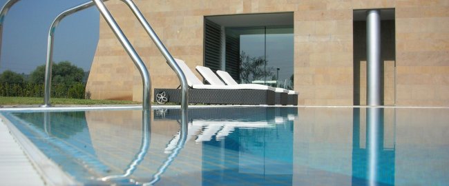 Piscina con sdraio bianche e edificio moderno.