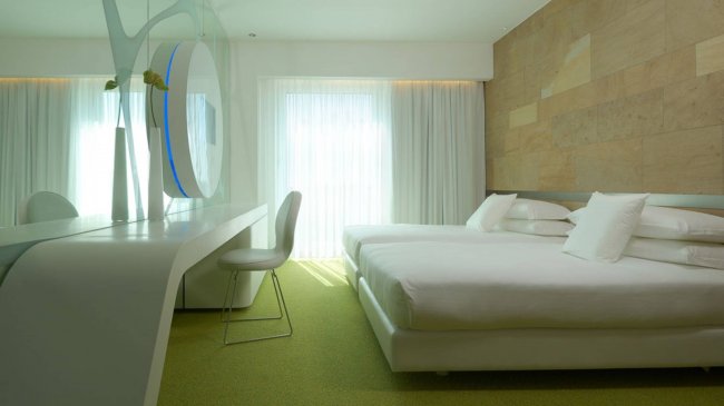 Una stanza luminosa con letto matrimoniale e specchio decorativo.