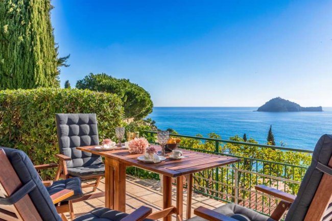 Terrazza con tavolo e sedie, affacciata sul mare.
