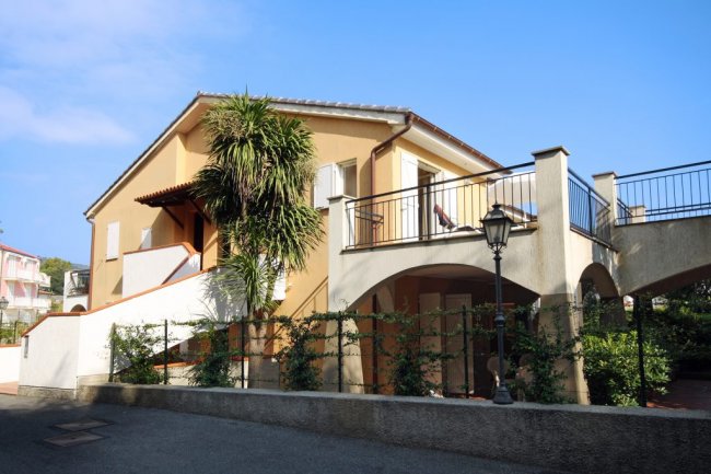 Edificio giallo con balcone e palme.