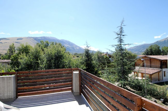 Vista su montagne e alberi da un terrazzo.