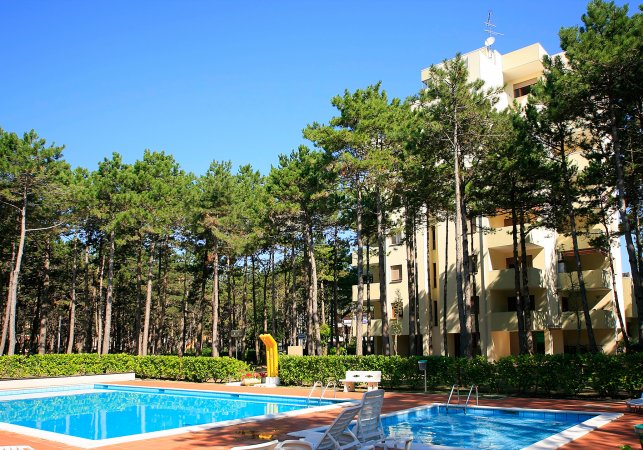 Piscine all'aperto vicino a un edificio giallo tra gli alberi.