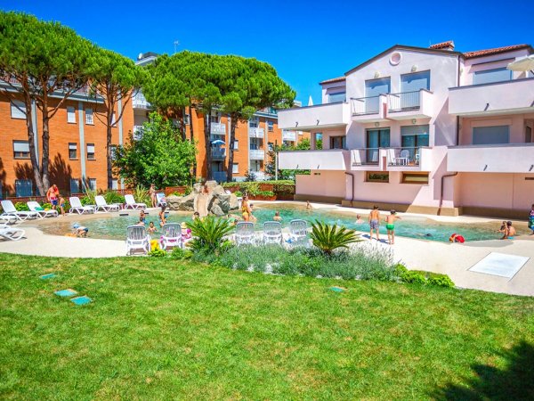 Piscina e giardini in un residence con alberi e lettini.