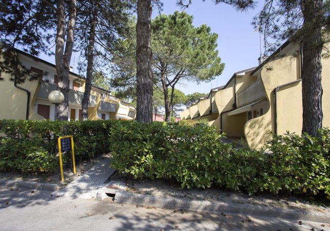 Edifici gialli tra alberi e siepi.