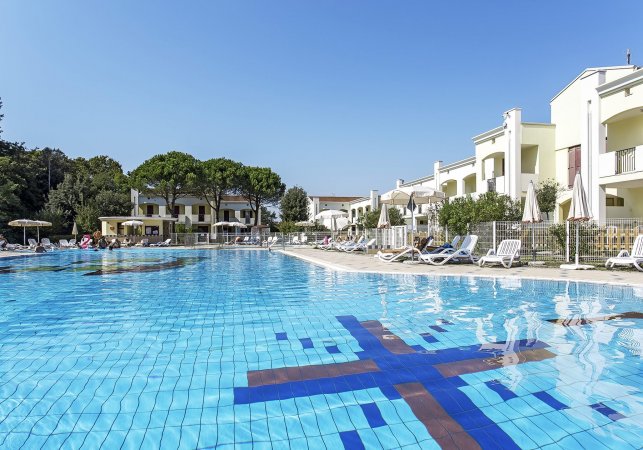 Piscina con lettini e palazzi bianchi.