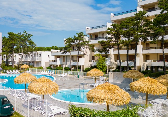 Piscina con ombrelloni di paglia e lettini.