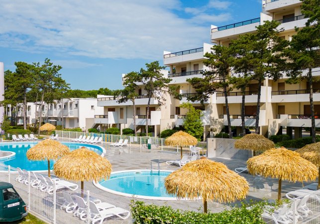 Piscina all'aperto circondata da ombrelloni di paglia.