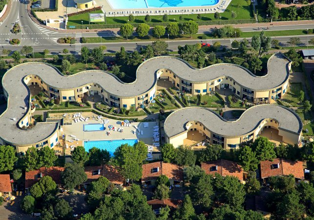 Vista aerea di complesso con tetto sinuoso e piscina.