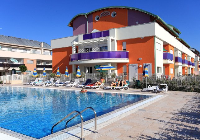 Piscina con lettini e ombrelloni colorati.