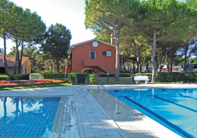 Piscina circondata da alberi e un edificio rosso.
