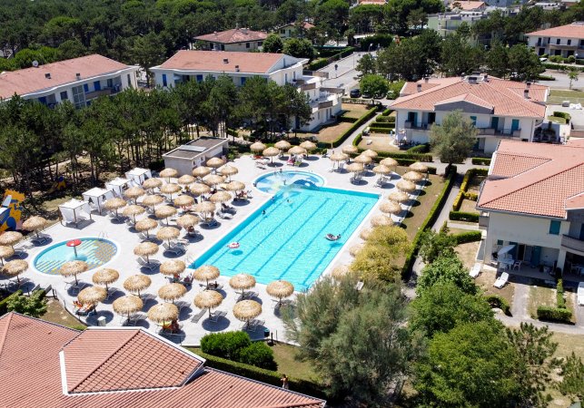 Piscina con ombrelloni e villette intorno.