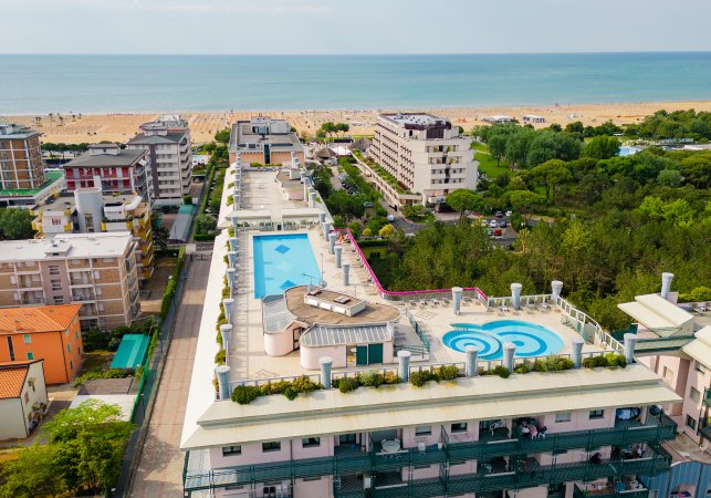 Vista aerea di un palazzo con piscina e spiaggia in lontananza.