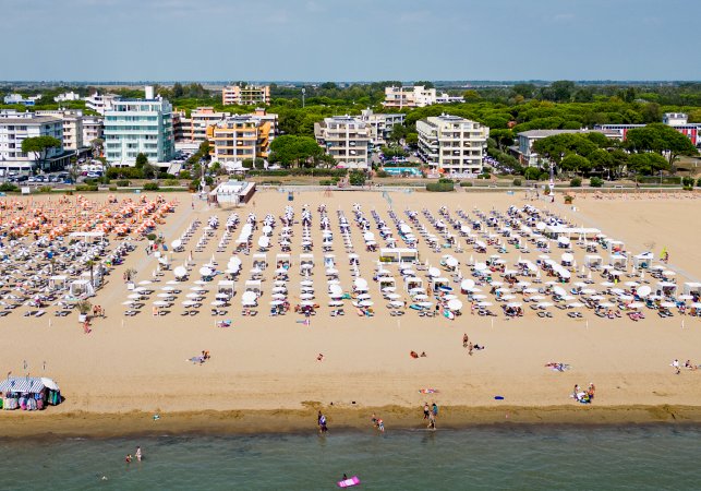 Spiaggia affollata con file di ombrelloni e mare.