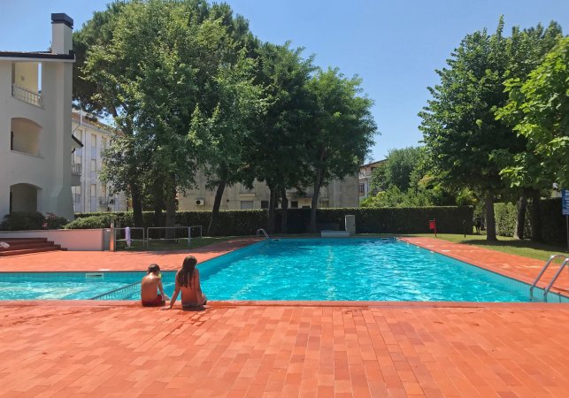 Piscina con due persone sedute sul bordo.