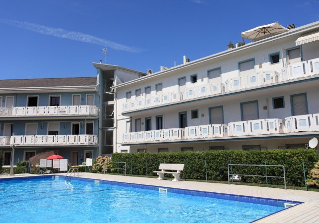 Edificio bianco a tre piani con piscina in primo piano.
