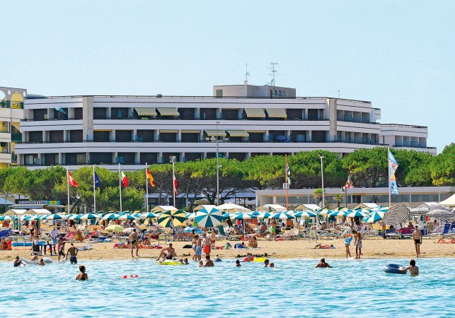 Spiaggia affollata, edificio bianco sullo sfondo.