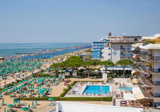 Spiaggia affollata con lettini e ombrelloni.