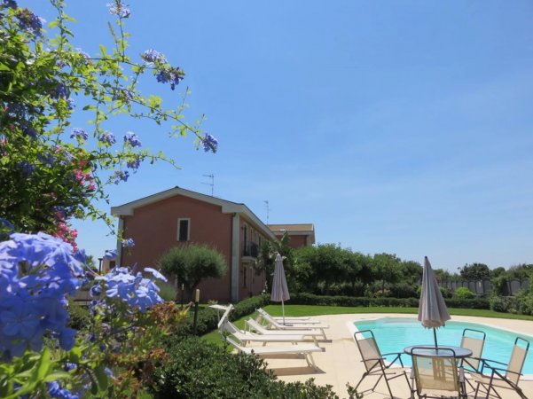 Piscina con lettini, ombrelloni e edificio rosso.