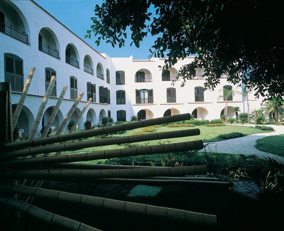 Edificio bianco con archi e giardino verde.