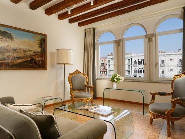 Elegante soggiorno con mobili dorati e finestre ad arco con vista sulla città.