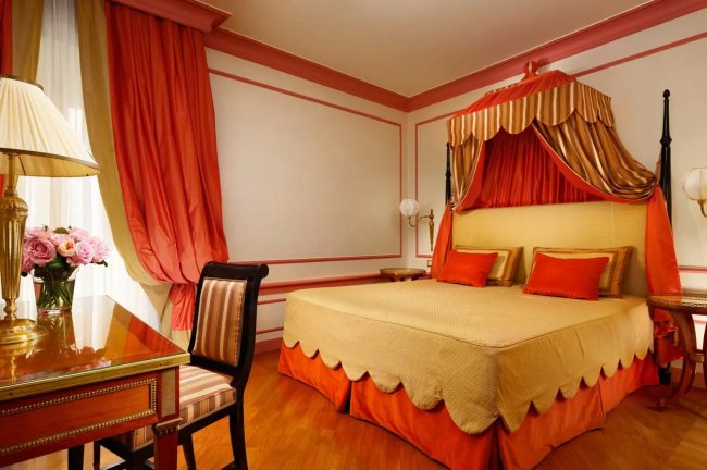 Camera con letto a baldacchino rosso e arancio.