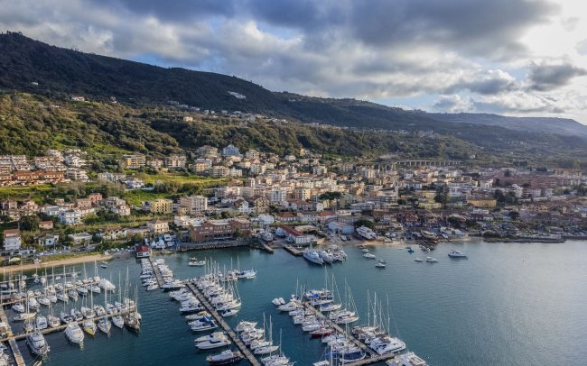 Vista aerea di una città costiera con porto e barche.