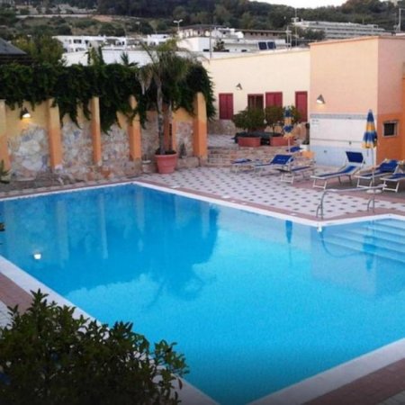 Piscina circondata da sedie e piante.